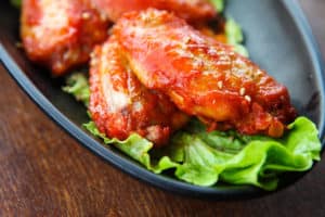 How Long to Air Fry Frozen Chicken Wings (buffalo wings on black plastic plate)